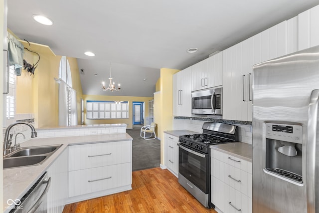 7412 Lattice Dr, Indianapolis, IN 46217 - kitchen featuring stainless steel appliances, a chandelier, light wood finished floors, light countertops, and white cabinets