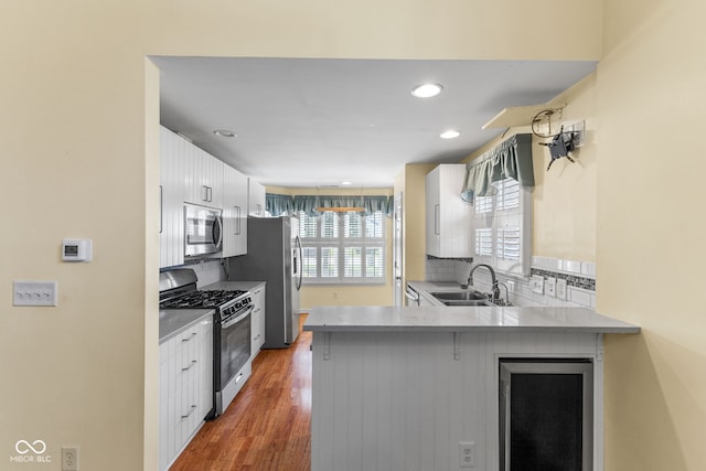7412 Lattice Dr, Indianapolis, IN 46217 - kitchen with stainless steel appliances, a peninsula, white cabinetry, decorative backsplash, and wood finished floors
