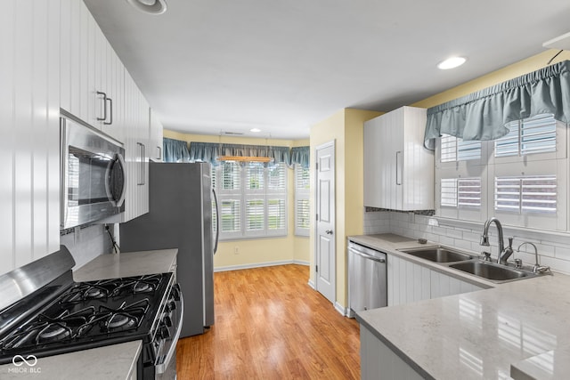 7412 Lattice Dr, Indianapolis, IN 46217 - kitchen with appliances with stainless steel finishes, decorative backsplash, light wood-type flooring, light countertops, and white cabinets