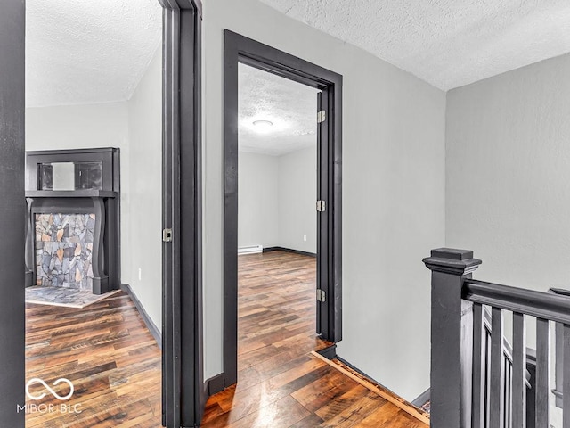 1126 N Rural St, Indianapolis, IN 46201 - hallway featuring a textured ceiling, wood finished floors, an upstairs landing, and a baseboard heating unit