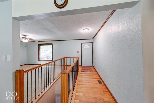 11 N Restin Rd, Greenwood, IN 46142 - corridor featuring a textured wall, light wood-style floors, crown molding, a textured ceiling, and an upstairs landing