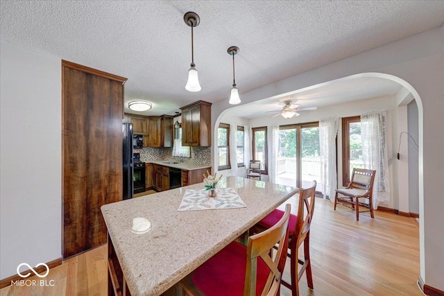 11 N Restin Rd, Greenwood, IN 46142 - kitchen featuring arched walkways, black appliances, a breakfast bar, pendant lighting, and a textured ceiling