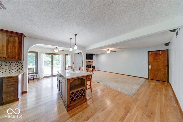 11 N Restin Rd, Greenwood, IN 46142 - dining room featuring ceiling fan, arched walkways, a fireplace, a textured ceiling, and light wood-style floors