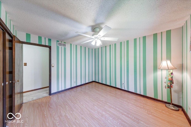11 N Restin Rd, Greenwood, IN 46142 - empty room with wood finished floors, a ceiling fan, wallpapered walls, and a textured ceiling