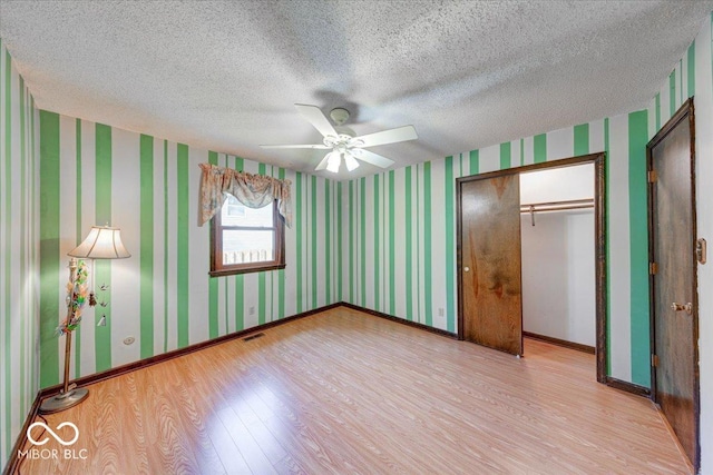 11 N Restin Rd, Greenwood, IN 46142 - unfurnished bedroom with light wood-style floors, a textured ceiling, wallpapered walls, a closet, and a ceiling fan