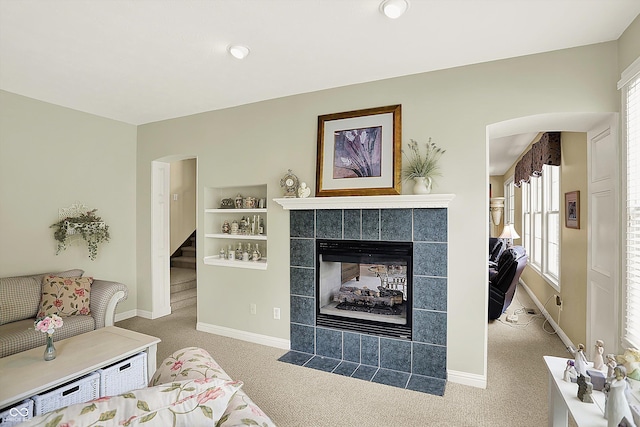 4704 Pearcrest Way, Greenwood, IN 46143 - carpeted living area featuring a tiled fireplace, plenty of natural light, stairway, and arched walkways