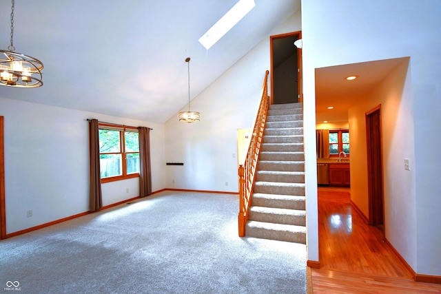 3363 Paddington Dr, Columbus, IN 47203 - stairway featuring high vaulted ceiling, a chandelier, a skylight, and wood finished floors