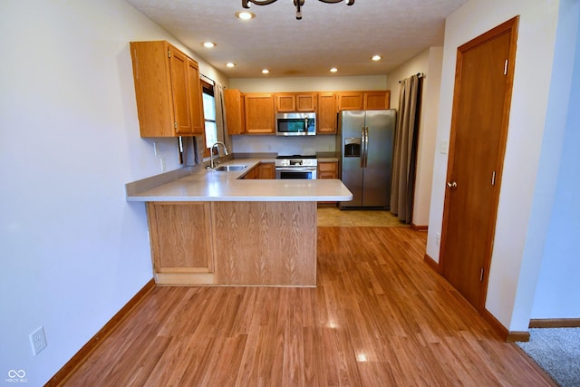 3363 Paddington Dr, Columbus, IN 47203 - kitchen featuring stainless steel appliances, a peninsula, light countertops, light wood-type flooring, and brown cabinetry