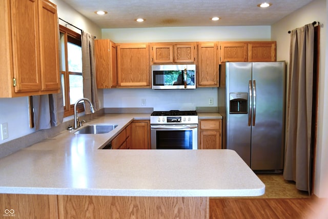 3363 Paddington Dr, Columbus, IN 47203 - kitchen with stainless steel appliances, light countertops, light wood-style floors, a peninsula, and brown cabinets