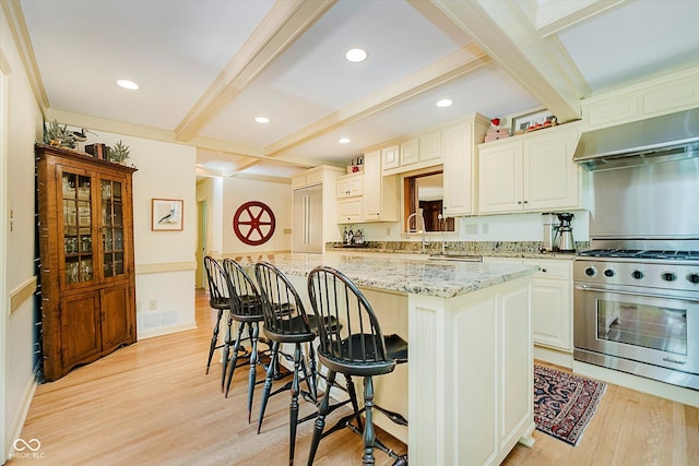6280 N Chester Ave, Indianapolis, IN 46220 - kitchen with stainless steel appliances, ventilation hood, beamed ceiling, a breakfast bar area, and light wood finished floors
