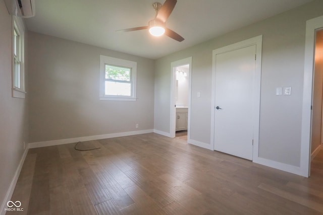 7300 N Banta Rd, Bargersville, IN 46106 - unfurnished bedroom with an AC wall unit, wood finished floors, ensuite bathroom, and ceiling fan
