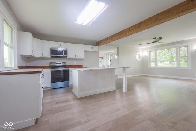 7300 N Banta Rd, Bargersville, IN 46106 - kitchen with appliances with stainless steel finishes, white cabinetry, open floor plan, light wood-type flooring, and beam ceiling