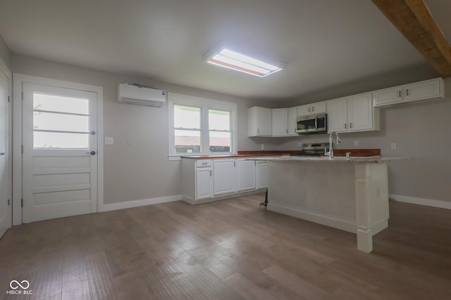 7300 N Banta Rd, Bargersville, IN 46106 - kitchen with appliances with stainless steel finishes, an AC wall unit, white cabinetry, light wood finished floors, and beam ceiling