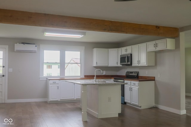 7300 N Banta Rd, Bargersville, IN 46106 - kitchen with appliances with stainless steel finishes, a wall unit AC, white cabinetry, beam ceiling, and an island with sink