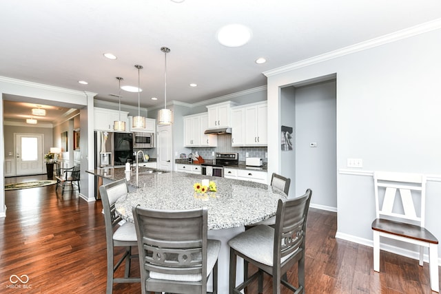 13427 Merryvale St, Fishers, IN 46037 - kitchen featuring appliances with stainless steel finishes, under cabinet range hood, a kitchen breakfast bar, backsplash, and recessed lighting