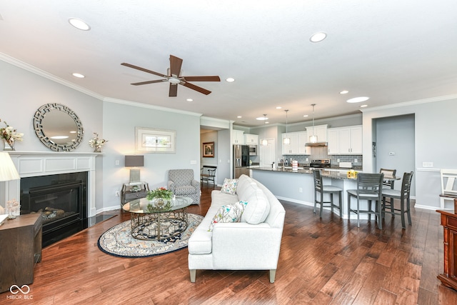 13427 Merryvale St, Fishers, IN 46037 - living area with ceiling fan, recessed lighting, dark wood-type flooring, ornamental molding, and a fireplace with flush hearth