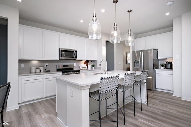 18980 Seaforth Way, Westfield, IN 46074 - kitchen featuring stainless steel appliances, tasteful backsplash, light wood-type flooring, an island with sink, and recessed lighting