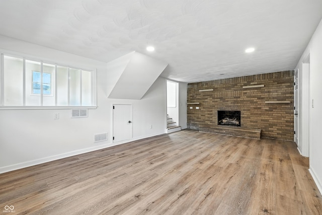 1011 Robin Dr, Anderson, IN 46013 - unfurnished living room with stairs, wood finished floors, recessed lighting, and a brick fireplace