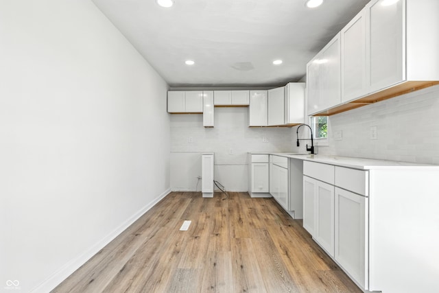 1011 Robin Dr, Anderson, IN 46013 - kitchen with recessed lighting, tasteful backsplash, light wood-type flooring, white cabinets, and light countertops