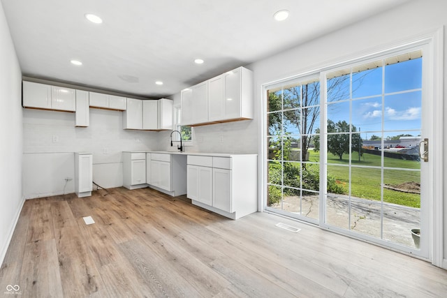 1011 Robin Dr, Anderson, IN 46013 - kitchen with light wood-style flooring, recessed lighting, white cabinetry, and tasteful backsplash