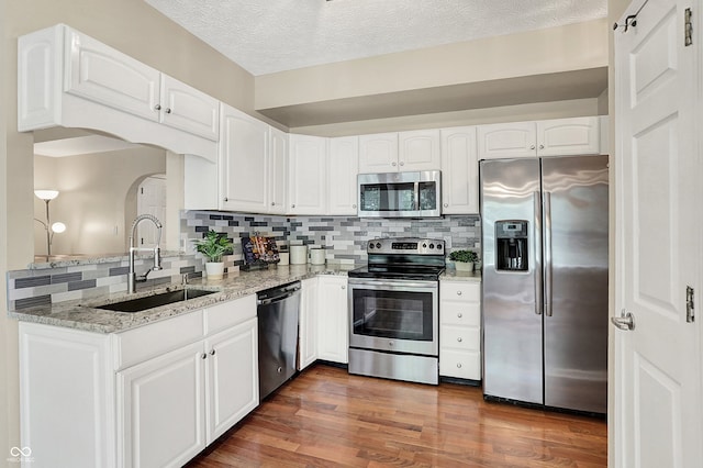 6298 Briargate Dr, Zionsville, IN 46077 - kitchen with appliances with stainless steel finishes, tasteful backsplash, light stone counters, white cabinetry, and arched walkways