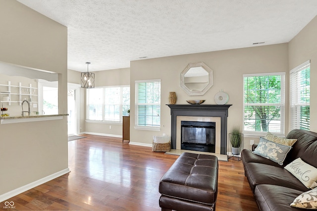 6298 Briargate Dr, Zionsville, IN 46077 - living room featuring wood finished floors, a glass covered fireplace, a textured ceiling, and a chandelier