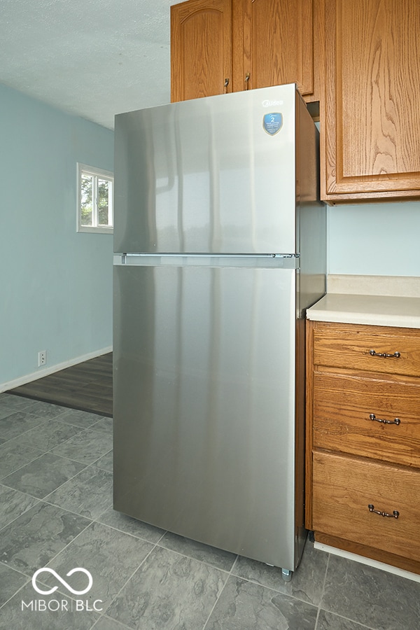 2606 Shakespeare Dr, Southport, IN 46227 - kitchen featuring freestanding refrigerator, light countertops, and brown cabinetry