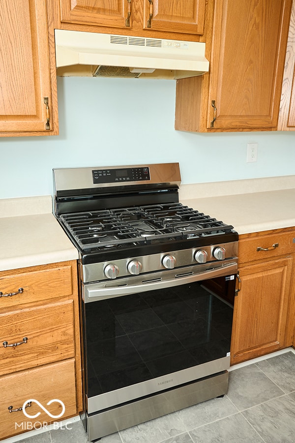 2606 Shakespeare Dr, Southport, IN 46227 - kitchen featuring stainless steel gas range, under cabinet range hood, light countertops, and light tile patterned floors