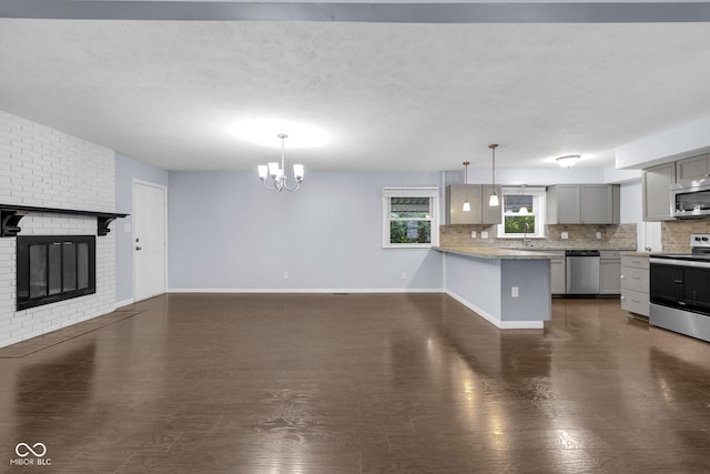 1231 N Graham Ave, Indianapolis, IN 46219 - unfurnished living room featuring a chandelier, a fireplace, dark wood finished floors, and a textured ceiling