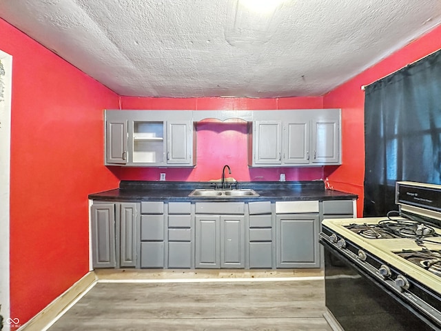 356 S 7th St, Frankfort, IN 46041 - kitchen with black gas range oven, light wood finished floors, dark countertops, a textured ceiling, and gray cabinets