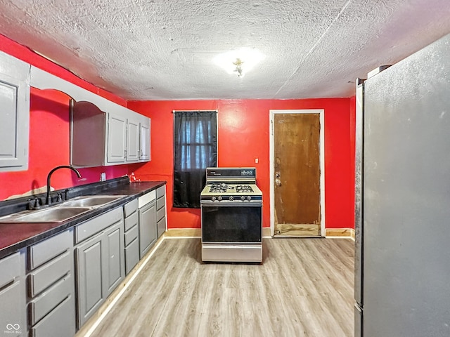 356 S 7th St, Frankfort, IN 46041 - kitchen featuring gas range oven, freestanding refrigerator, light wood finished floors, dark countertops, and a textured ceiling