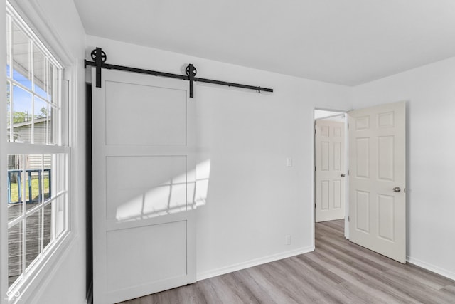 2829 Dakota Dr, Anderson, IN 46012 - unfurnished bedroom featuring a barn door and light wood-style flooring