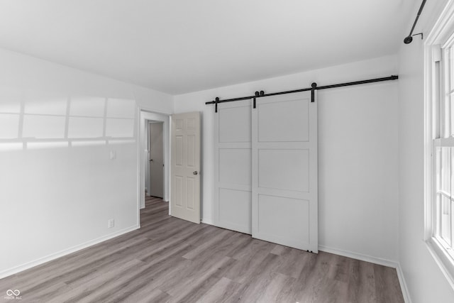2829 Dakota Dr, Anderson, IN 46012 - unfurnished bedroom with a barn door and light wood-style flooring
