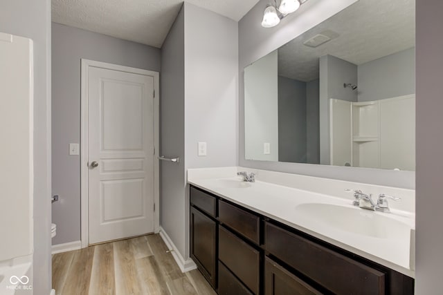 14620 Hinton Dr, Fishers, IN 46037 - bathroom with wood finished floors, double vanity, a shower, and a textured ceiling
