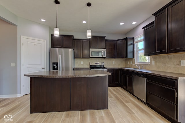 14620 Hinton Dr, Fishers, IN 46037 - kitchen with stainless steel appliances, light wood finished floors, dark brown cabinets, a kitchen island, and recessed lighting