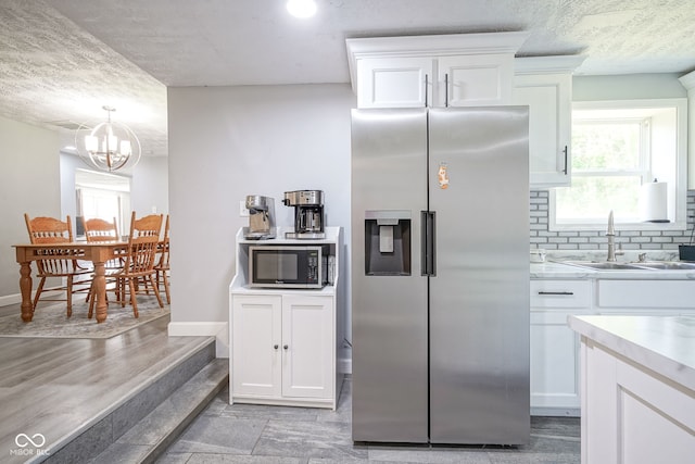 5902 Oak Ln, Anderson, IN 46013 - kitchen featuring appliances with stainless steel finishes, light countertops, white cabinetry, backsplash, and a textured ceiling