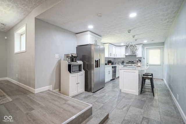 5902 Oak Ln, Anderson, IN 46013 - kitchen with appliances with stainless steel finishes, white cabinetry, light countertops, wall chimney range hood, and a breakfast bar area