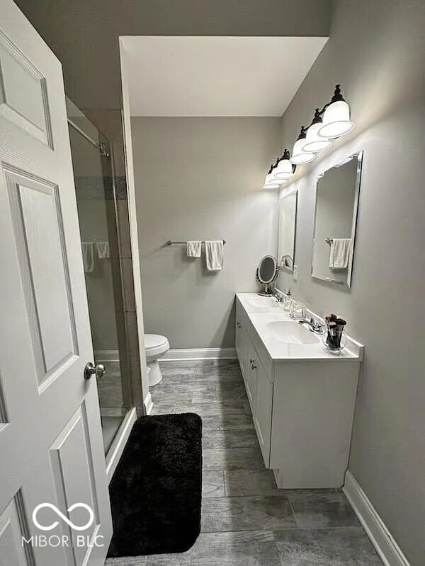 4155 Graceland Ave, Indianapolis, IN 46208 - bathroom with double vanity, a shower stall, and wood finished floors