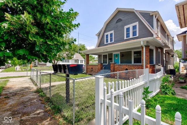 4155 Graceland Ave, Indianapolis, IN 46208 - dutch colonial featuring a porch, brick siding, a gambrel roof, and a fenced front yard