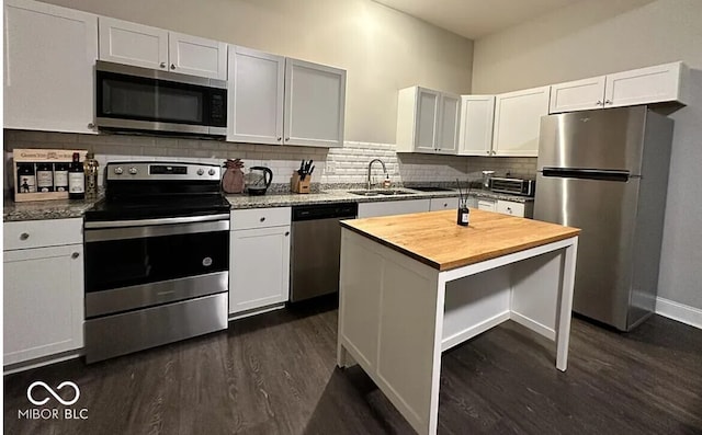 4155 Graceland Ave, Indianapolis, IN 46208 - kitchen featuring stainless steel appliances, butcher block countertops, dark wood-type flooring, decorative backsplash, and white cabinetry