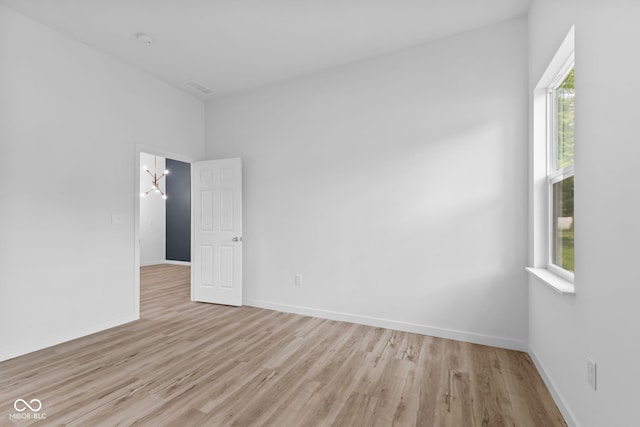 2709 Station St, Indianapolis, IN 46218 - empty room featuring light wood finished floors, a smoke detector, and a chandelier