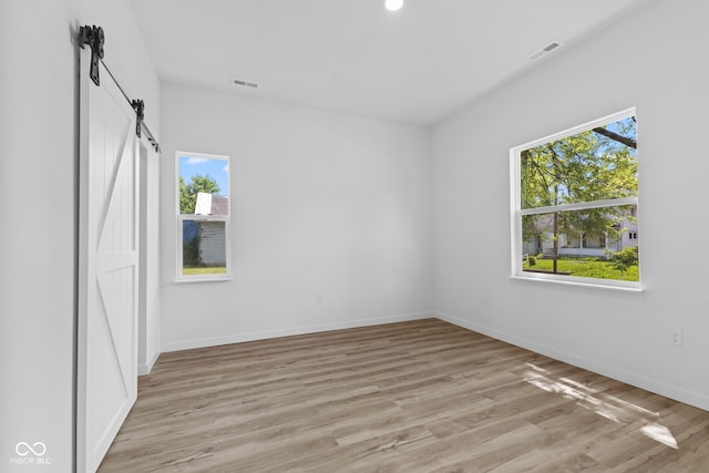 2709 Station St, Indianapolis, IN 46218 - unfurnished bedroom with light wood finished floors, a barn door, and recessed lighting