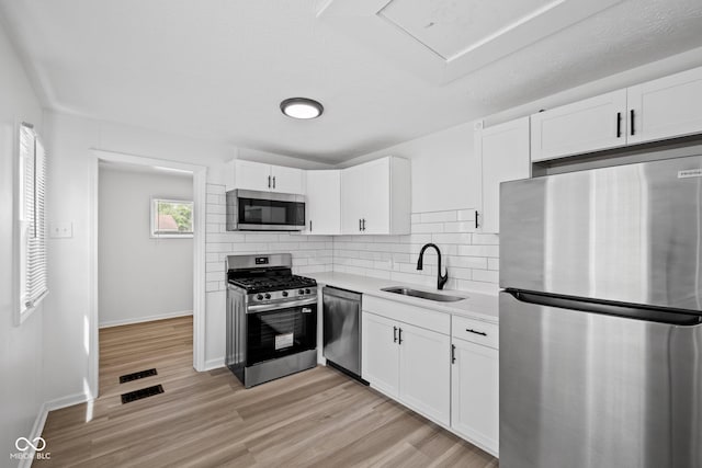 1730 S State Ave, Indianapolis, IN 46203 - kitchen with stainless steel appliances, white cabinets, light countertops, tasteful backsplash, and light wood finished floors