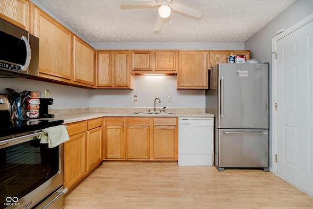 4020 Eisenhower Dr, Indianapolis, IN 46254 - kitchen with stainless steel appliances, light countertops, light wood finished floors, a ceiling fan, and a textured ceiling