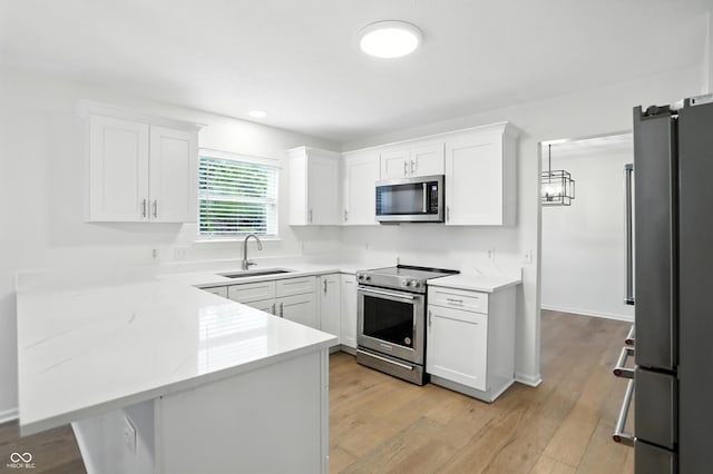 13264 Penneagle Dr, Carmel, IN 46033 - kitchen with appliances with stainless steel finishes, a peninsula, white cabinetry, light wood-type flooring, and recessed lighting