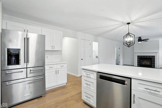 13264 Penneagle Dr, Carmel, IN 46033 - kitchen featuring stainless steel appliances, light countertops, light wood finished floors, white cabinetry, and a chandelier