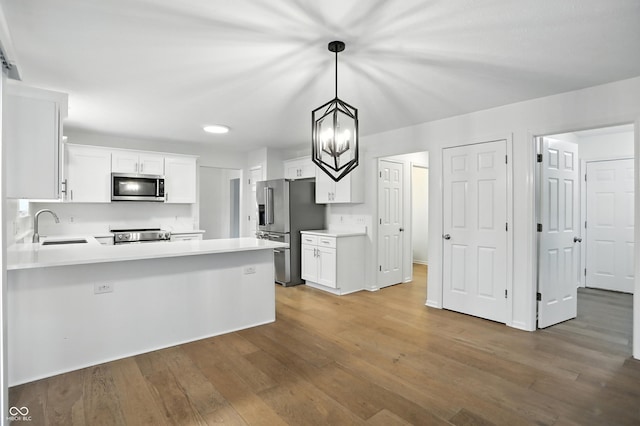 13264 Penneagle Dr, Carmel, IN 46033 - kitchen with stainless steel appliances, wood finished floors, light countertops, a peninsula, and white cabinets