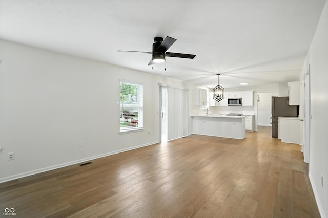 13264 Penneagle Dr, Carmel, IN 46033 - unfurnished living room featuring a chandelier, a ceiling fan, and light wood-style floors