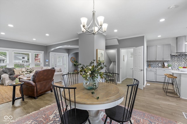 1141 W 35th St, Indianapolis, IN 46208 - dining space with crown molding, light wood-type flooring, arched walkways, recessed lighting, and a chandelier