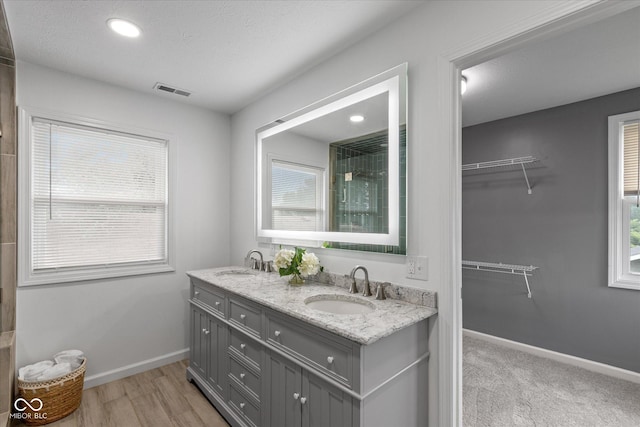 1141 W 35th St, Indianapolis, IN 46208 - bathroom featuring double vanity, a walk in closet, wood finished floors, recessed lighting, and tiled shower